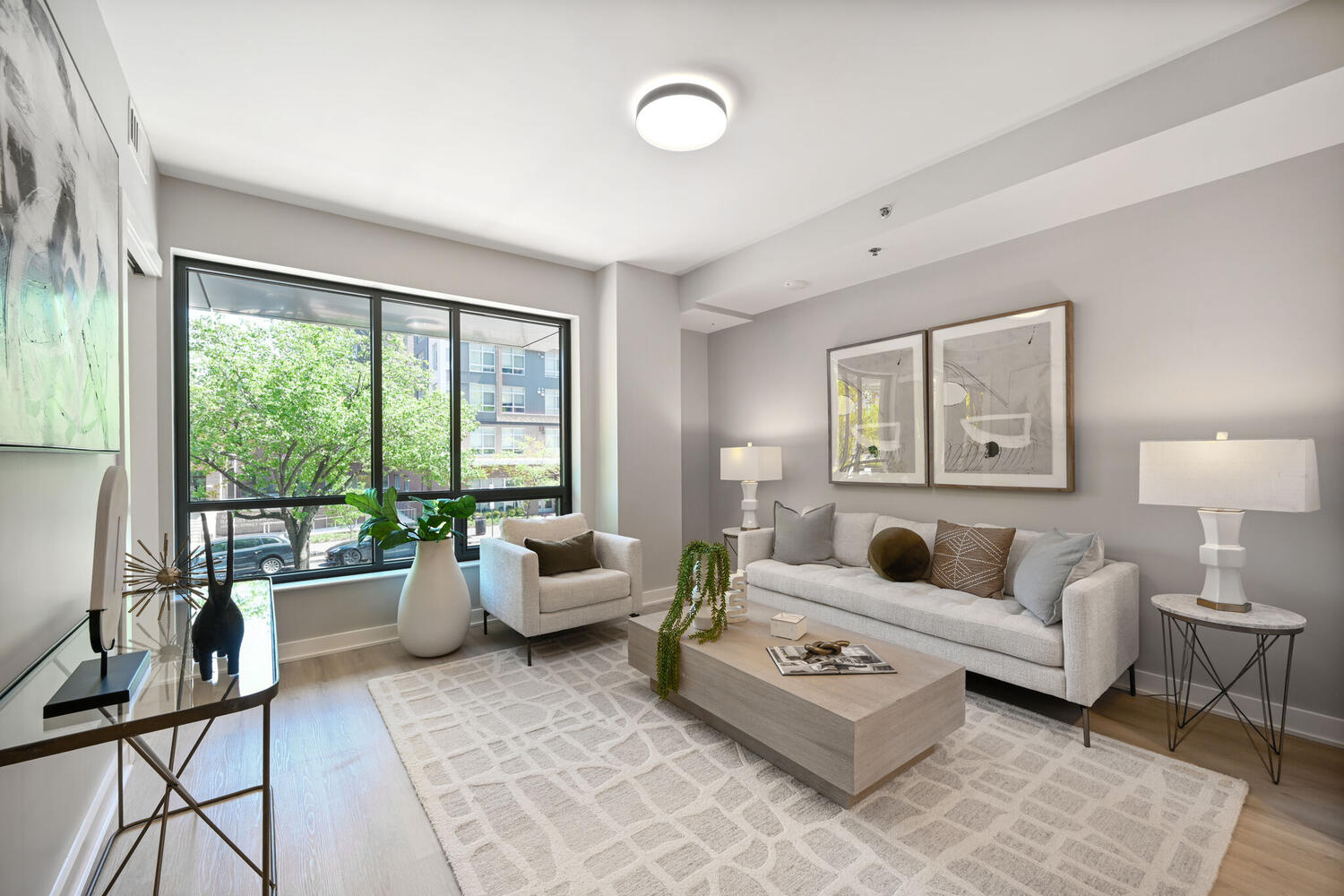 Mount Vernon Triangle, Washington, DC, Luxury Apartments Near Safeway - Claret - Living Room With Luxury Plank Flooring, Couch, Armchair, Round Coffee Table, Side Table, Lamps, And Large Windows.